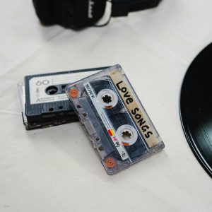 Flat Lay Of Nostalgic Cassette Tapes Labeled 'Love Songs' With Black Headphones And Vinyl Record.