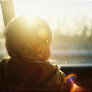 Serene Backlit Image Capturing A Baby Gazing Through A Car Window At Sunset.