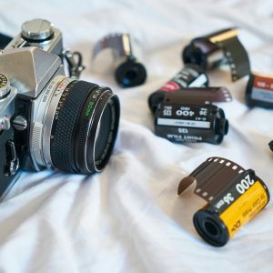 A Classic Film Camera Surrounded By Various Film Rolls, Evoking A Retro Photography Vibe.
