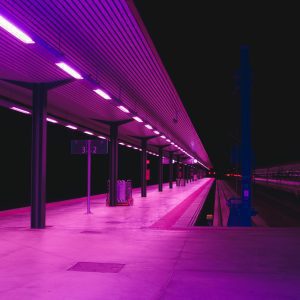 Explore The Vibrant Neon Lit Train Station Platform In Toledo At Night, Showcasing Urban Architecture.