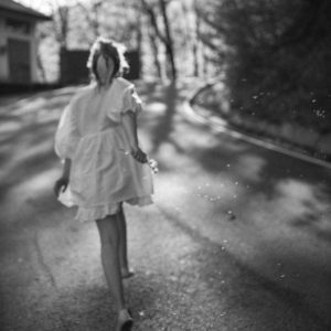 A Stylish Woman In A White Dress Walking On A Sunny Road, Creating A Serene Monochrome Scene.