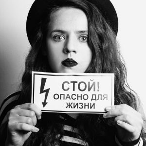 Hispanic Woman With Curly Hair Holding A Danger Sign In A Striking Black And White Portrait.