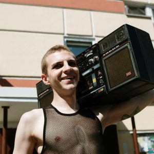 Smiling Man With Vintage Boombox In Urban Setting, Enjoying Music Outdoors.