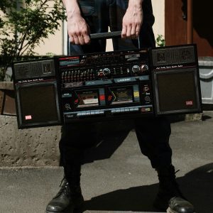 A Man Holds A Classic Vintage Boombox Outdoors, Evoking Retro Vibes And Nostalgia.