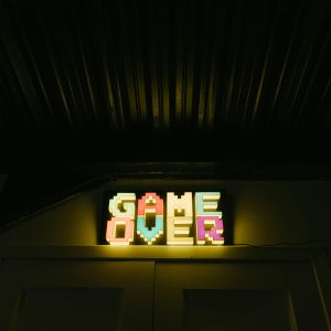 Glowing Neon Sign With Pixelated Game Over Text In A Dark Arcade Setting.