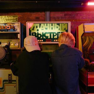 Teenagers Enjoying A Fun Time At A Retro Arcade With Vintage Gaming Machines.
