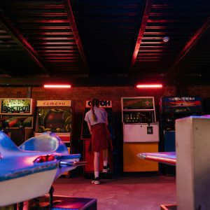 A Teenager With Pigtails Plays Classic Arcade Games In A Vintage Setting.