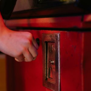 Hand Inserting Coin Into A Vintage Arcade Machine. Nostalgic Gaming Moment Captured Indoors.