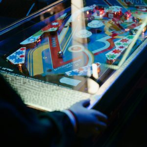 Colorful Vintage Pinball Machine Illuminated In A Retro Arcade Setup With A Player Engaging.
