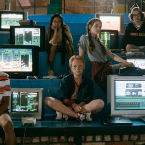 Group Of Teenagers Interacting With Old School Video Game Consoles, Evoking 80s Nostalgia.