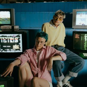 Teenagers Enjoying Retro Video Games In A Vintage Arcade Setting, Wearing Colorful Outfits.