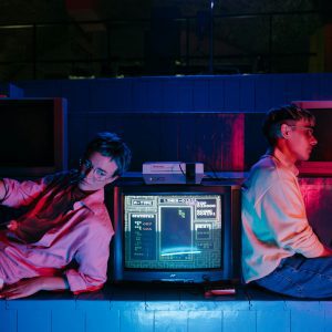 Teenagers Enjoying Retro Gaming On Vintage Screens With Neon Lights. Nostalgic 80s Vibe.