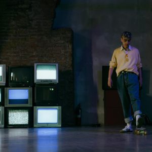 A Teenager Skates Near Vintage CRT TVs Displaying Static In A Dimly Lit Room.