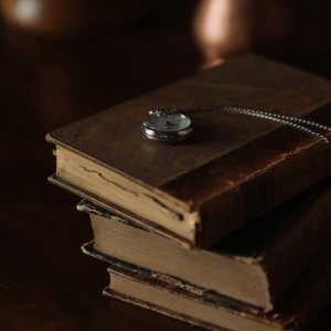 An Elegant Pocket Watch Gracefully Rests Atop A Stack Of Antique Books In A Vintage Still Life Setting.