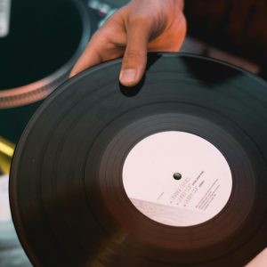 A Close Up Shot Of A Hand Holding A Vinyl Record Ready To Play On A DJ Mixer.