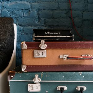 Stack Of Vintage Suitcases Against A Rustic Blue Brick Wall, Ideal For Travel Themes.