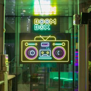 Bright Neon Sign Of A Boom Box Illuminating A Storefront At Night.