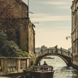 Captivating View Of A Venetian Canal With A Bridge And Boat, Showcasing Historic Architecture.
