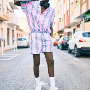 Stylish Young Man Wearing Striped Outfit, Holding A Boombox, Smiling In An Urban Street.