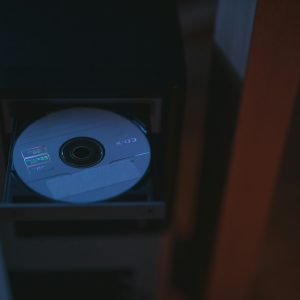 A Close Up Image Of A CD Partially Ejected From A Drive, Showcasing Soft Lighting.