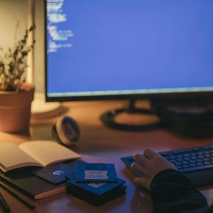 A Home Office Setup With A Computer Screen Displaying Code, Captured At Night.