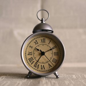 Close Up Of An Antique Alarm Clock Displaying Time With Classic Roman Numerals.