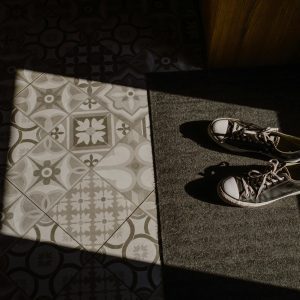 A Pair Of Vintage Sneakers On A Stylish Patterned Tile Floor With Dramatic Lighting And Shadows.
