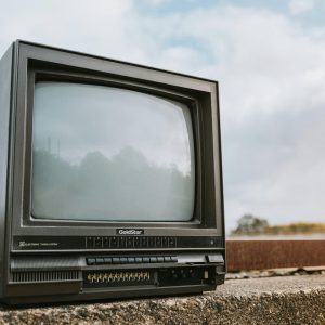 Old CRT Television Set Placed Outdoors With A Cloudy Sky Backdrop, Evoking Nostalgia.