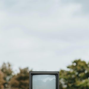 A Vintage TV Sits On A Concrete Wall Outdoors With Trees Blurred In The Background.