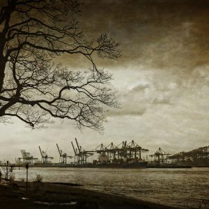 Dramatic Monochrome View Of A Harbour With Cranes Silhouetted Against A Cloudy Sky.
