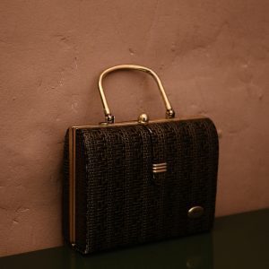 Vintage Bag With Golden Handle Placed On Reflecting Surface As Accessory For Garment