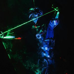 A Striking Image Of A Futuristic Performer In A Neon Costume Playing A Musical Instrument With Lasers In A Dark Setting.