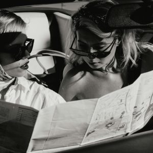 Two Stylish Women Reading A Map Inside A Vintage Convertible. Black And White Photo.