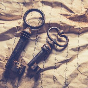 Vintage Iron Keys Resting On Crumpled, Handwritten Paper With A Rustic Texture.