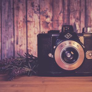 A Vintage Camera With Flowers Against A Rustic Wooden Backdrop, Exuding Nostalgia.