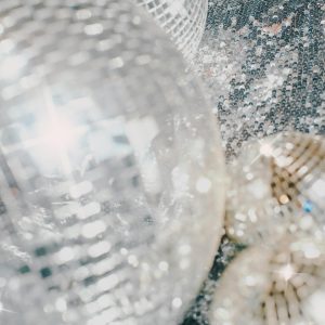 Close Up Of Shiny Disco Balls On A Sequin Surface, Creating A Festive And Luminous Atmosphere Indoors.