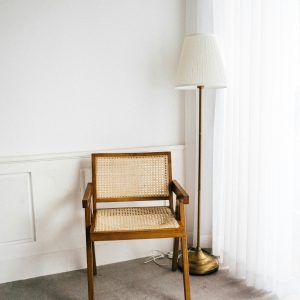 Stylish Minimalist Corner Featuring A Wooden Chair And Floor Lamp Against Bright Curtains.