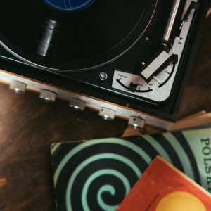 Top View Of A Classic Turntable Playing A Vinyl Record With Retro Album Covers Nearby.