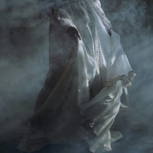 A Figure Dances In A Misty Room Wearing A Vintage White Dress, Evoking A Timeless Elegance.