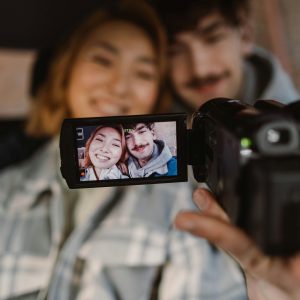 A Couple Films Themselves With A Video Camera, Capturing A Joyful Moment Indoors.