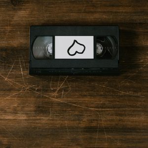 A Nostalgic VHS Tape With A Heart Shaped Label On A Rustic Wooden Surface.