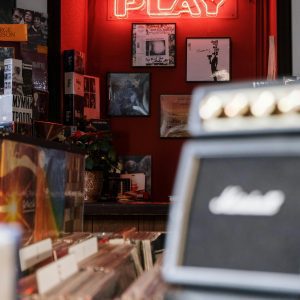 Explore A Retro Vinyl Record Store Featuring A Glowing Neon 'Play' Sign And Vintage Albums.