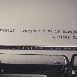 Vintage Typewriter Displaying Oscar Wilde's Quote 'Be Yourself, Everyone Else Is Already Taken.'