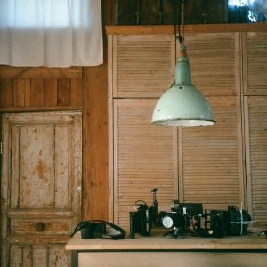 A Cozy Indoor Space Featuring A Vintage Lamp, Cameras, And Rustic Wooden Decor.