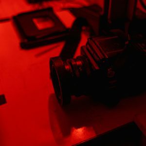 A Vintage Film Camera On A Table In A Darkroom With Red Lighting, Conveying A Nostalgic Atmosphere.