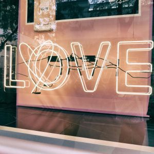 Neon 'LOVE' Sign In A Modern Urban Window Display With Reflections.