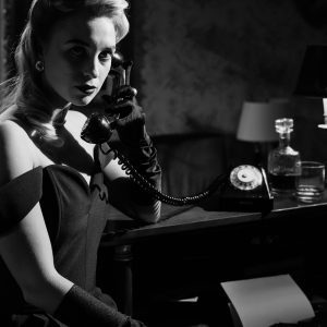 Elegant Woman In Classic Attire Using Rotary Phone, Evoking Noir Ambiance.