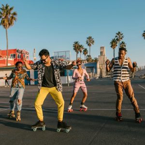 Young Adults Roller Skating At Venice Beach, Enjoying A Vibrant Sunny Day Outdoors.