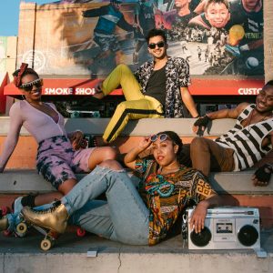 Group Of Young Adults Roller Skating In A Lively Urban Area With Vibrant Streetwear.