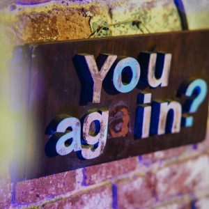 Colorful Sign On A Brick Wall With The Text 'You Again?' Creating A Vintage Vibe.